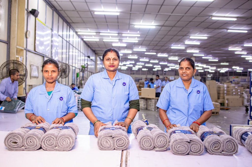 Women sorting towels in a bright, organized textile factory setting.